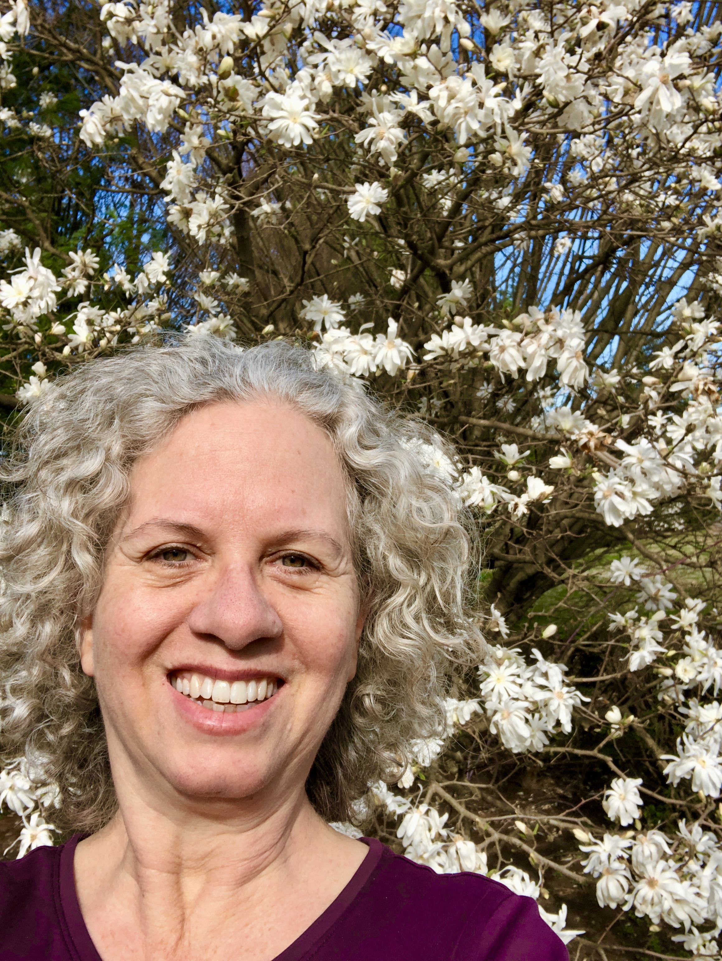 author, poet, musician, podcast host, course creator Jenny Leigh Hodgins in front of a star magnolia tree.