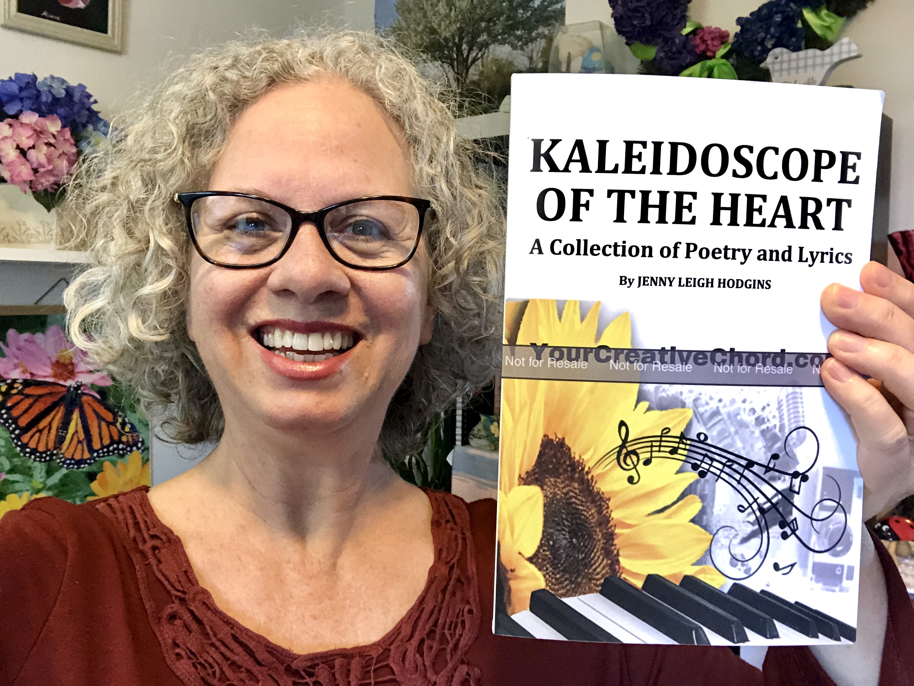 author, poet, musician, podcast host, course creator Jenny Leigh Hodgins holding her poetry book proof..